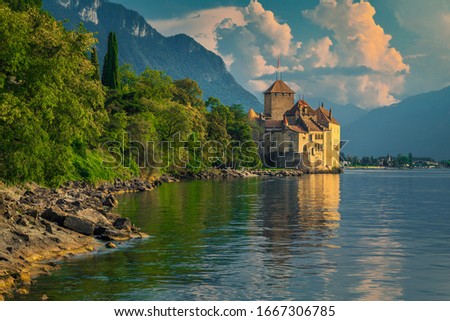 Popular Swiss touristic location with famous picturesque Chillon castle at Geneva lake and high mountains in background at sunset, Montreux, Switzerland, Europe