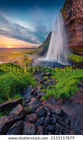 Popular tourist attraction - Seljalandsfoss waterfall, where tourists can walk behind the falling waters. Amazing summer scene of Iceland, Europe. Beauty of nature concept background.