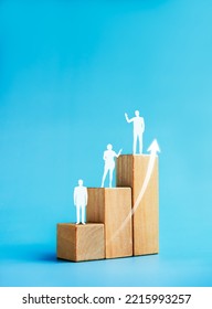 Population increase, people evolution chart, leadership concept. Rise up arrows and human icon standing on a growth graph chart steps arranged by wood cube blocks on blue background, vertical style. - Shutterstock ID 2215993257
