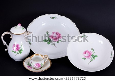 Porcelain set with floral pattern, home kitchenware objects made of composition on black background, antique porcelain set buying now. 