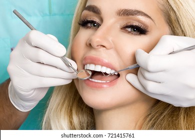 Porcelain veneers. Pretty female model with perfect smile. Young beautiful woman with beautiful white teeth sitting on a dental chair. Teeth whitening.