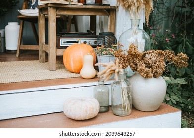 Porch Of The Backyard Decorated With Pumpkins And Dry Grass In Autumn, Rustic Furniture On Veranda Of A Rustic House, A Cozy And Stylish Interior In Autumn Colors