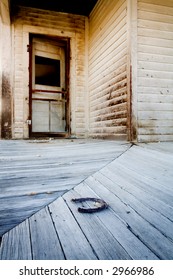 Porch Of A Supposed Old Haunted House In Rural Wyoming With A Rusty Horse Shoe Laying On Floor. Focus On The Horse Shoe.