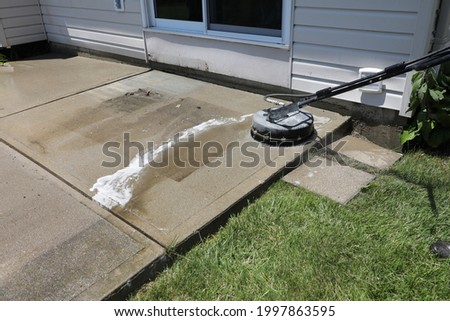 A porches is cleaned using a surface washer.