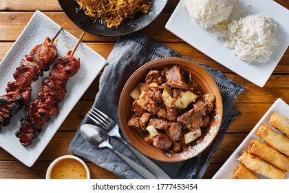 Pork Adobo Meal With Filipino Foods Such As Lumpia, Pancit Noodles, And Rice