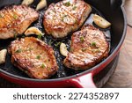 Pork chops cooked with garlic in a cast iron pan
