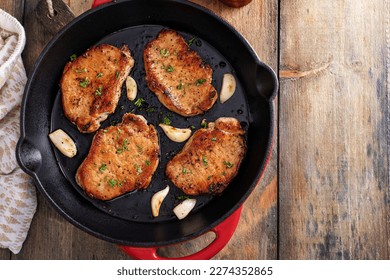 Pork chops cooked with garlic in a cast iron pan