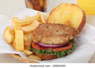 Pork Fritter With Lettuce, Tomato And Onion On A Toasted Bun With French Fries