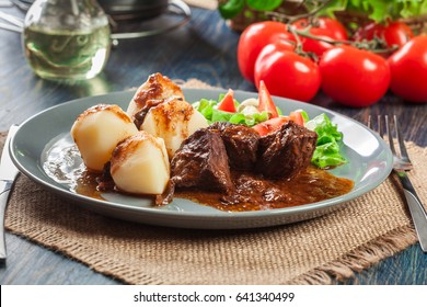 Pork Meat Stew Served With Potatoes And Vegetable Salad On A Plate. Side View.