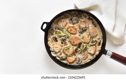 Pork medallions with mushroom sauce in cast iron pan over white stone background with copy space. Top view, flat lay