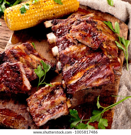 Pork ribs with corn on a wooden board. American food. View from above.