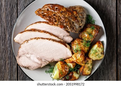 Pork Roast, Pork Shoulder Roasted Whole In The Oven Served With Potato On A Plate On A Dark Wooden Table, Horizontal View From Above, Flat Lay, Close-up