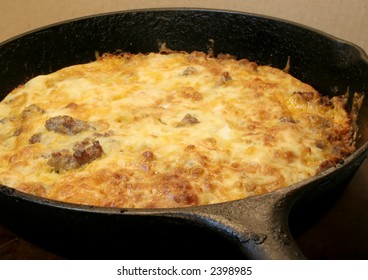 Pork Sausage, Biscuit Mix, And Cheddar Cheese Casserole In A Black Cast Iron Skillet.