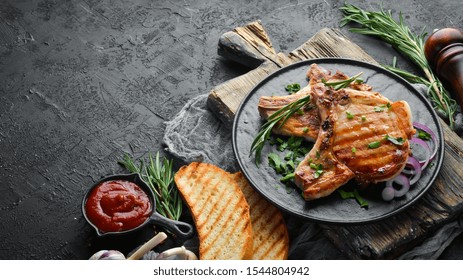 Pork Steak On A Bone With Rosemary And Greens In A Black Plate. Top View. Free Copy Space.