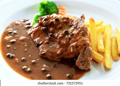 Pork Steak Set With The Black Pepper Sauce On White Plate, Potato Or French Fries And Some Vegetable As Foods Background.