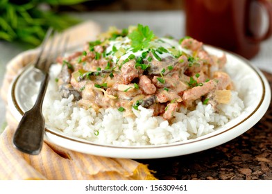 Pork stroganoff with sour cream, fresh greens and chopped gherkin on rice