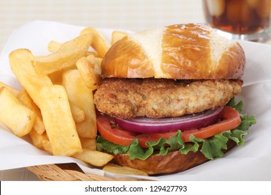 Pork Tenderloin Sandwich On A Bun With French Fries In A Basket