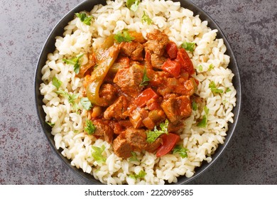 Porkolt Is Hungarian For Beef Stew Made By Braising Meat And Simmering It With Onions, Paprika In A Tomato Based Sauce Served With Egg Noodles Nokedli Closeup On The Plate On The Table. Horizontal Top