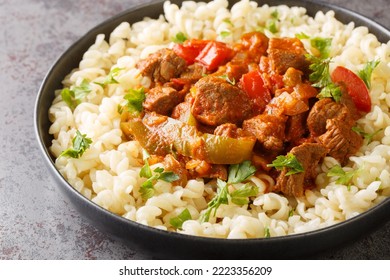 Porkolt Is Hungarian For Beef Stew Made By Braising Meat And Simmering It With Onions, Paprika In A Tomato Based Sauce Served With Egg Noodles Nokedli Closeup On The Plate On The Table. Horizontal
