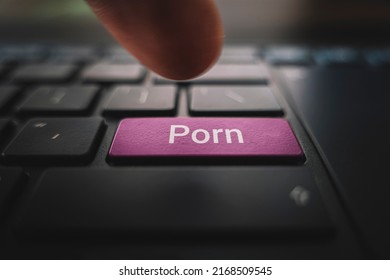 porn button on keyboard. A male finger presses a color button on a keyboard a modern laptop. Button with inscription close up. Watching pornography on a computer.