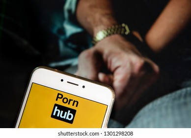 Pornographic video sharing website Pornhub logo is seen on an Android mobile device with a couple holding hands image in the background.