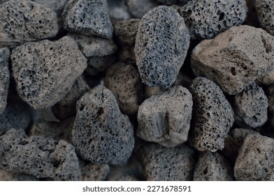 Porous black volcanic rock isolated on white background. Lava stone, pumice stone, or volcanic pumice with distinctive pores.