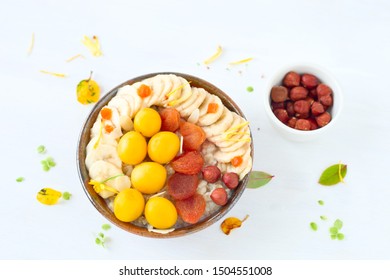 Porridge with banana slices, dried apricot and yellow plums - Shutterstock ID 1504551008