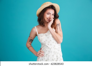 Porrtrait of a smiling playful shy woman wearing summer clothes isolated over blue background
