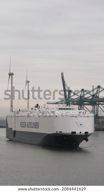 Port of Antwerp, Belgium - 11 24\
2021: Pure car carrier leaving the port and bound for sea. Ro-ro\
vessel with the cargo of cars underway to the next\
destination.
