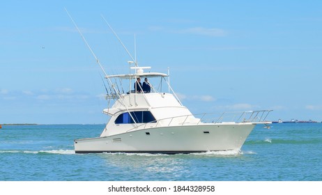 PORT ARANSAS, TX - 29 FEB 2020: Angled view of a beautiful white fishing yacht boat sails on the calm blue water as it approaches the marina on a sunny day.