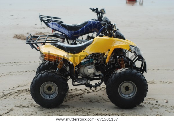Port Dickson,\
Malaysia - August 08, 2017: Yellow & Blue (Autonomous Terrain\
Vehicle) ATV for rental at\
Beach.