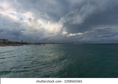 Port Elizabeth Coastline With Seaport And City View In The Distance Against Dramatic Clouds On The Background