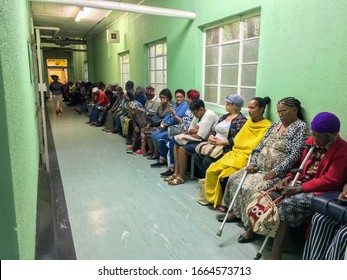 Port Elizabeth, SOUTH AFRICA - March 2020: Queue of seated outpatients, waiting patiently inside Provincial Hospital corridor