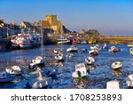 Port at low tide at the end of the sunny day and church of Saint-Nicolas of Barfleur, a commune in the peninsula of Cotentin in the Manche department in Lower Normandy in north-western France