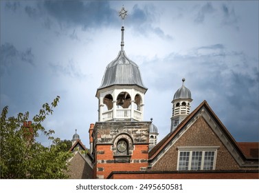 Port Sunlight, Wirral, UK - July 26th 2024 -The lead domes and a bell on the roof tops of a school on top of a clock tower - Powered by Shutterstock