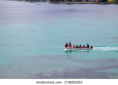 PORT VILA, VANUATU - MAY 22, 2020: Small Red Boat Carrying Several Ni-Vanuatu People Across A Reef