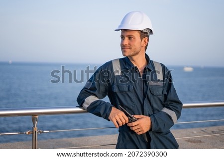 Port worker with VHF radio on embankment