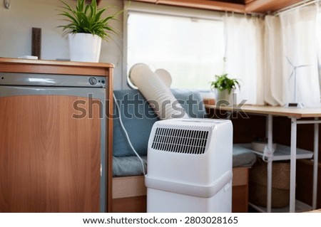 Portable air conditioner unit operating inside a modern camper van during a summer heatwave