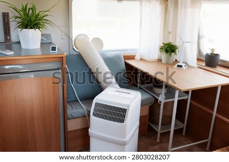 Portable air conditioner unit operating inside a modern camper van during a summer heatwave
