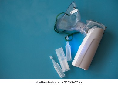 Portable breathing machine with mask on blue background. Apparatus on battery can hold in hand, used at home or road. Breathing device for asthma and recovering after coronavirus. Close-up. - Shutterstock ID 2119962197