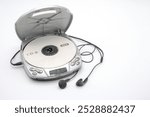 Portable CD player with the lid open with a CD and headphones isolated on white background