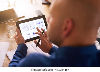 Portable Computer Tablet Being Used By A Caucasian Male Business Executive During A Board Meeting To View Live Analysis Of The Company's Investment Portfolio.