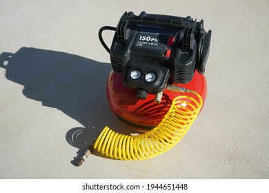 A Portable Electric Air Compressor With Coiled Hose.