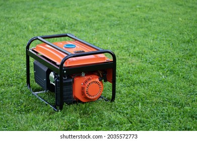 Portable electric generator on the green grass outdoors in summer