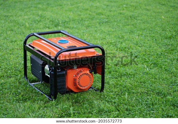 Portable electric generator on the green grass\
outdoors in summer