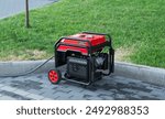 Portable electric generator on the street in summer day. The generator provides with electricity electrical appliances in nature.