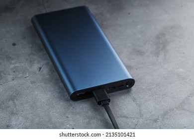 Portable External Battery Power Bank blue with USB Cord on a dark textured background for charging Gadgets