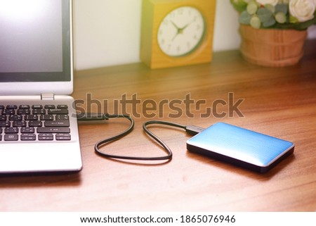 Portable external hard drive USB3.0 connect to laptop computer on desk, Data transfer or backup personal files concept