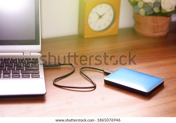 Portable\
external hard drive USB3.0 connect to laptop computer on desk, Data\
transfer or backup personal files\
concept