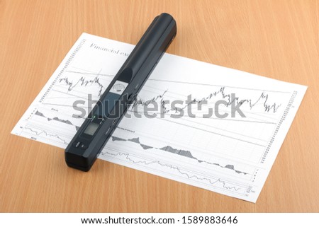 A portable handheld black scanner for documents and papers located on the document. 